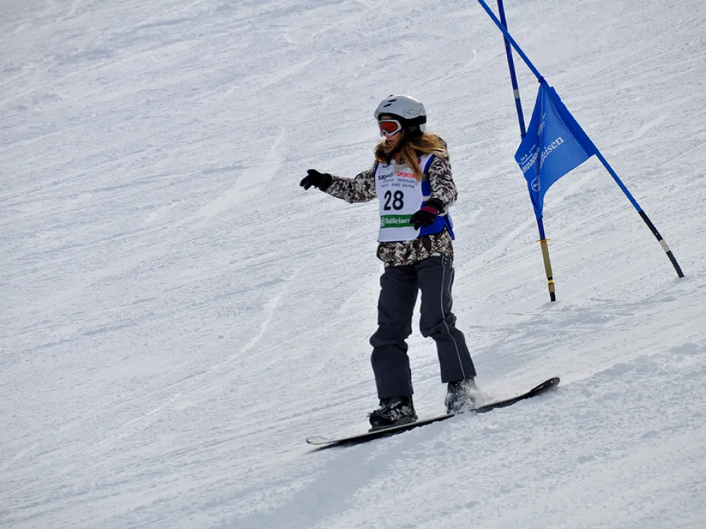 Snowboarderin mit Startnummer 28 fährt durch das Tor.